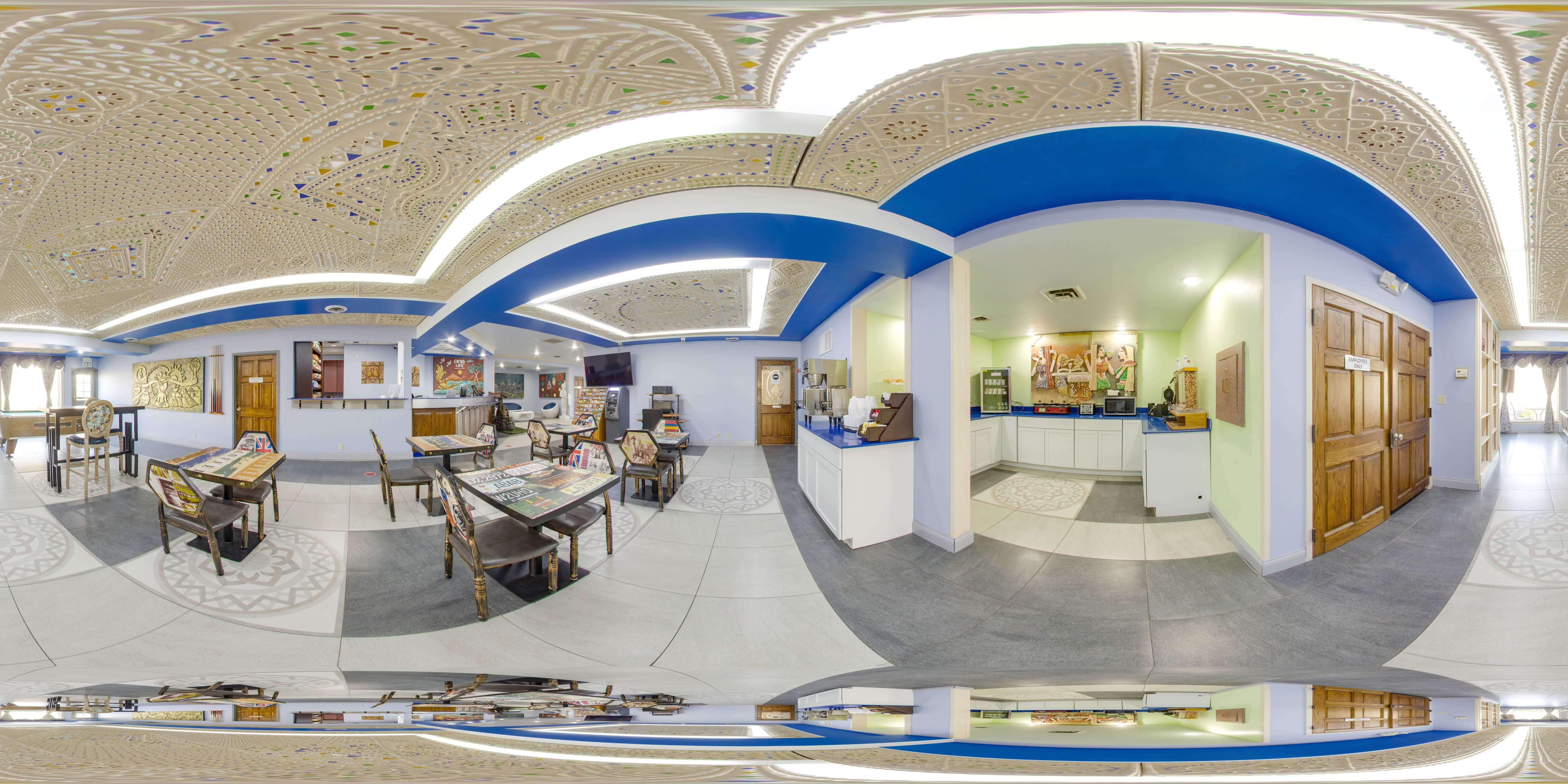 A wide-angle view of a lobby with a reception desk, seating area, and decorative ceiling.