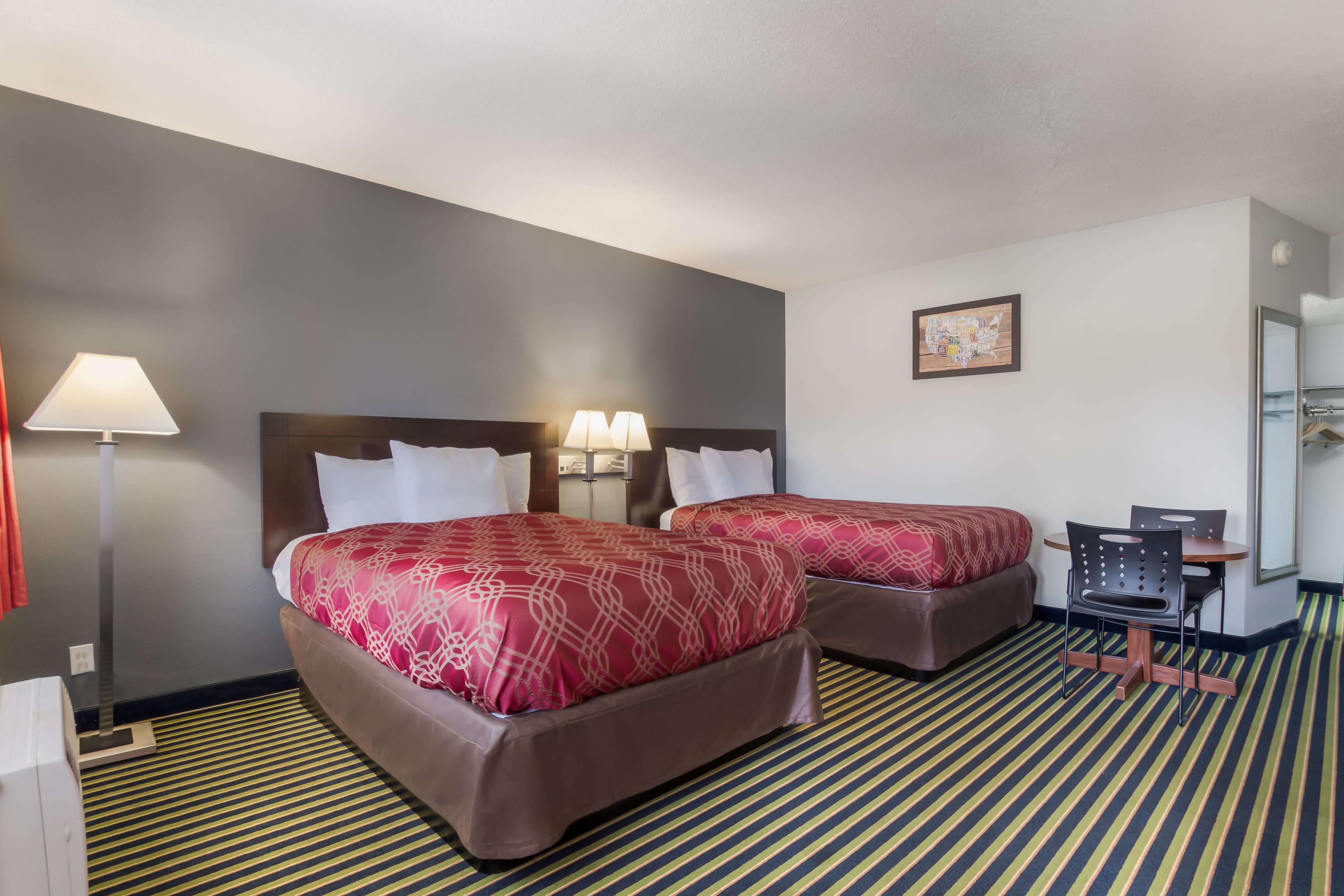 A hotel room with two beds, a desk, and a TV.